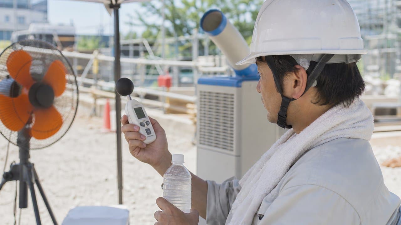 建設現場でWBGT計を確認しながら休憩を取る作業員