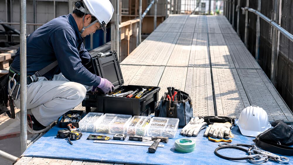 建築現場の作業台まわりで工具箱とツールボックスを整理する様子