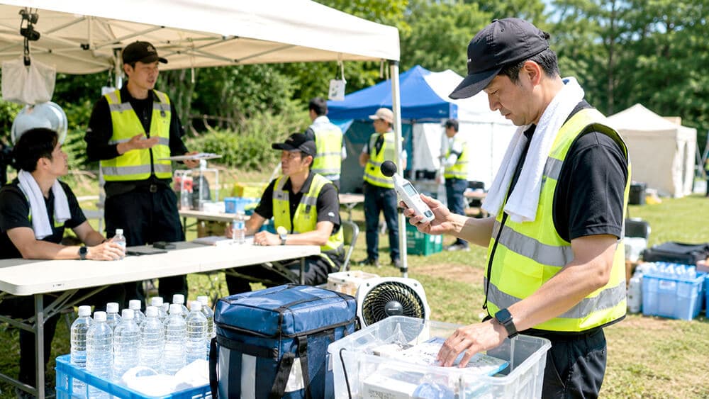 屋外イベント会場でスタッフの熱中症対策を確認する責任者