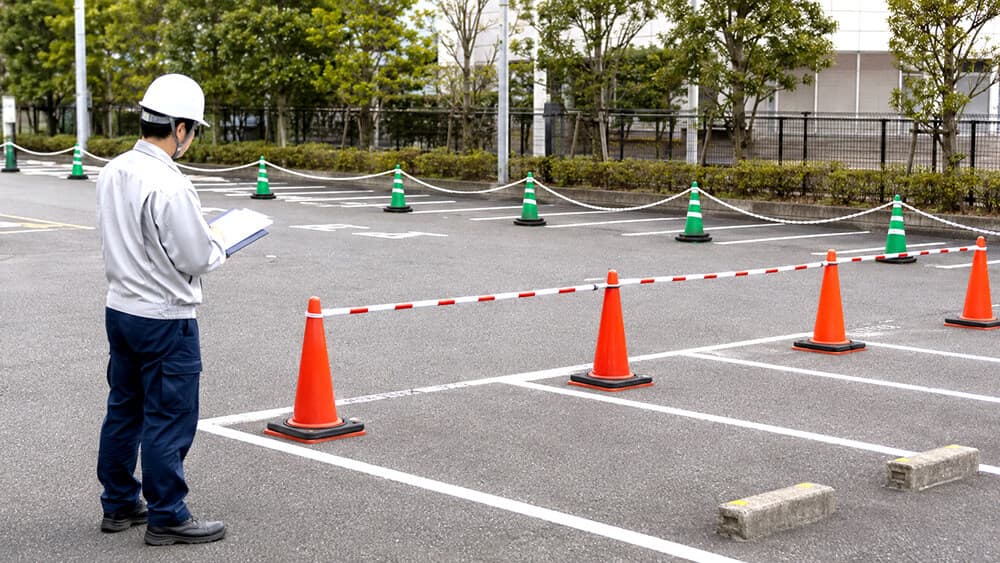駐車場でコーンバーとプラチェーンを用途別に使い分ける様子