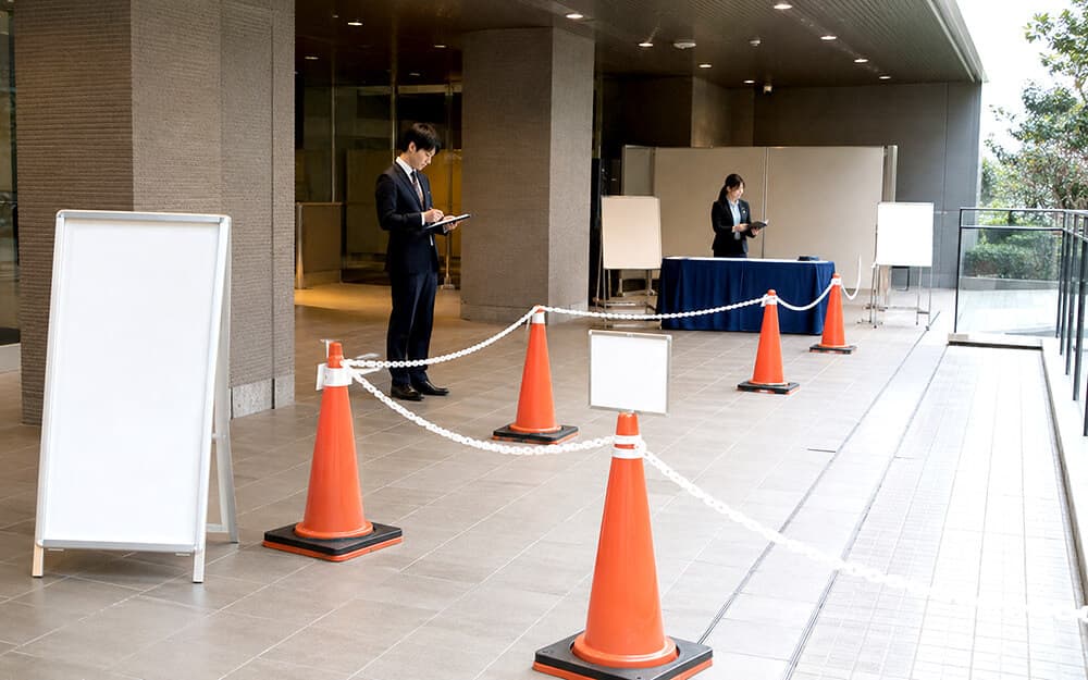 イベント会場でカラーコーンとプラチェーンを使って来場者導線を作る様子