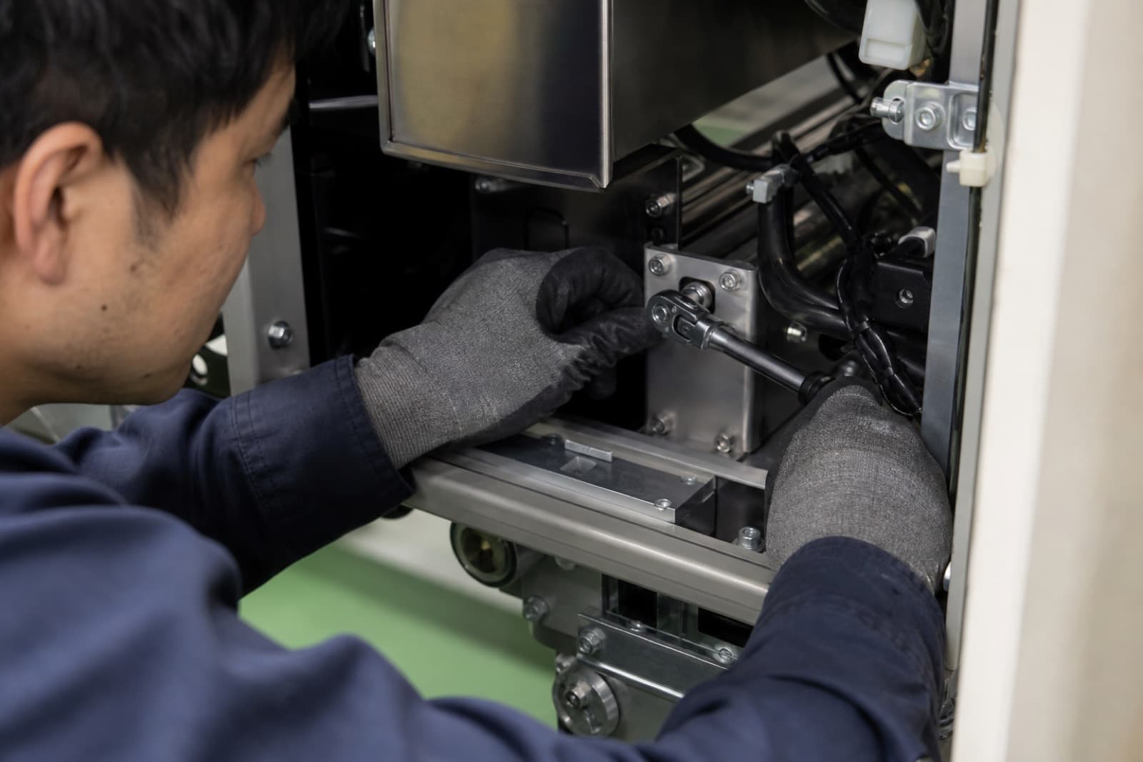 狭い機械内部で首振りラチェットを使ってボルトを締める作業イメージ