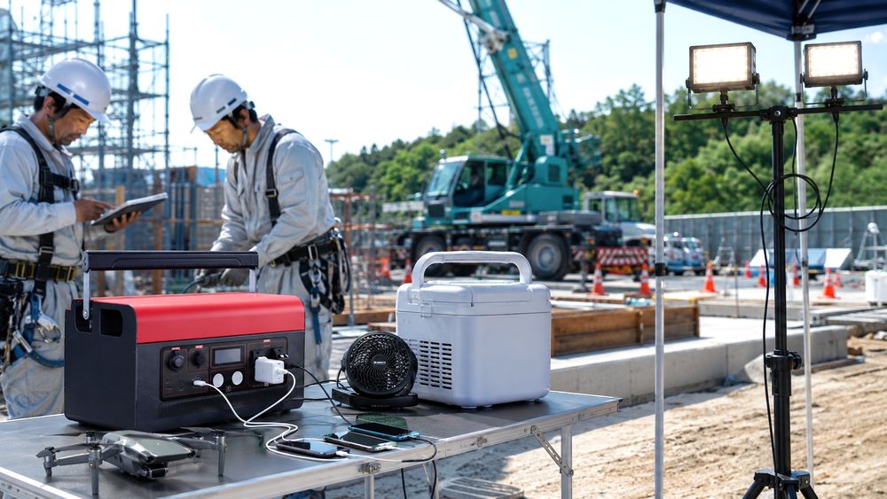 工事現場でポータブル電源を使って照明や冷温庫に給電するイメージ
