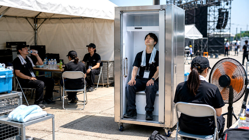 屋外イベントのスタッフ休憩所で暑さ対策設備を活用する様子